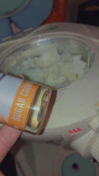 a person holding a tube of sugar in front of a toaster