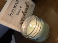 a candle on a wooden table with a sign that says less week more weekend