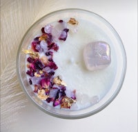 a candle with rose petals and crystals in it