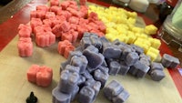 a tray of colored wax cubes on a cutting board