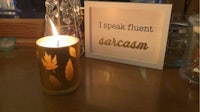a candle sits on a table next to a framed sign