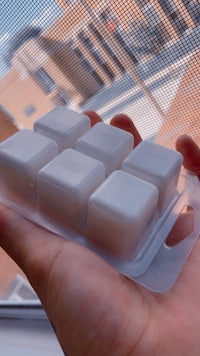 a person holding a package of small squares of soap